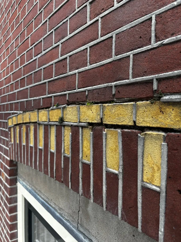 Voorsituatie: sierelement boven raam met scheurvorming en verweerde voegen