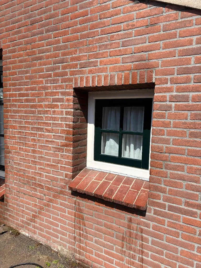 Dezelfde raamzone na reiniging met frissere, egale baksteen en schone voeg