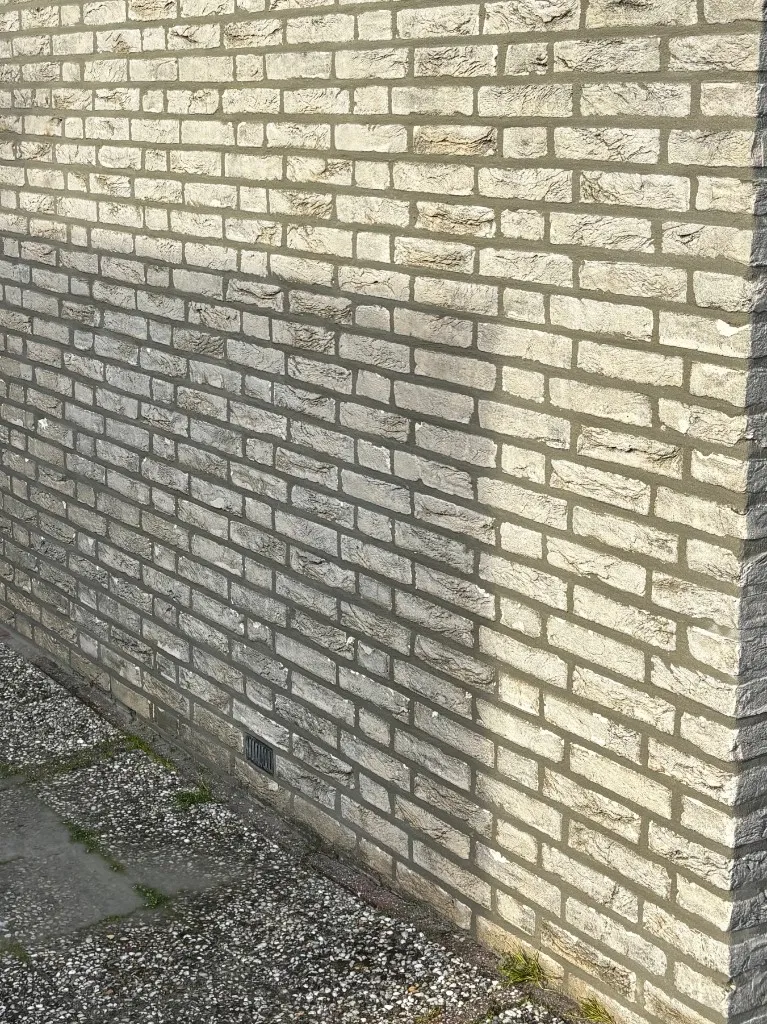 Na: dezelfde gevel met strak platvol voegwerk op de lichte baksteen