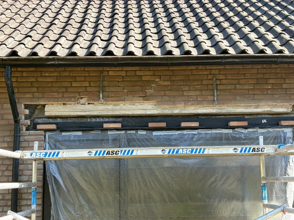 Stalen L-latei en DPC-folie aangebracht boven kozijn, vastgezet met bitumenplakband