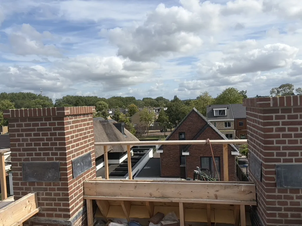 Twee nieuwbouw schoorstenen met licht verdiepte voeg boven de daklijn in Dordrecht