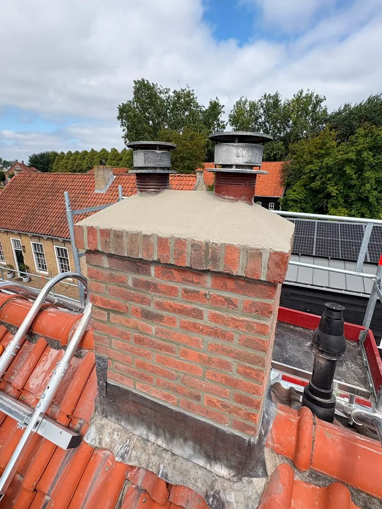 Gerenoveerde schoorsteen met opnieuw gevoegd metselwerk en een nieuwe betonnen afdekvloer