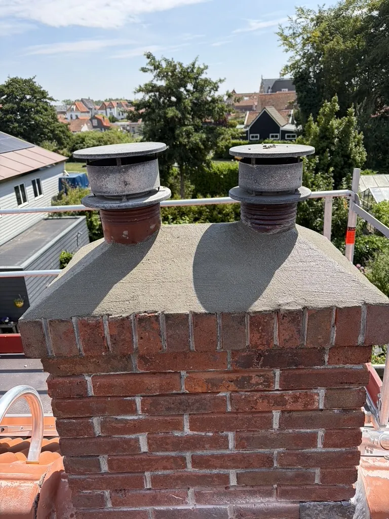 Afgewerkte schoorstenen met nieuw voegwerk en nieuwe betonnen afdekvloer boven het metselwerk