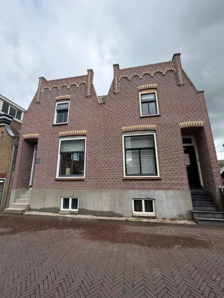 Dubbele topgevel na revisie: strak snijvoegwerk op rode baksteen