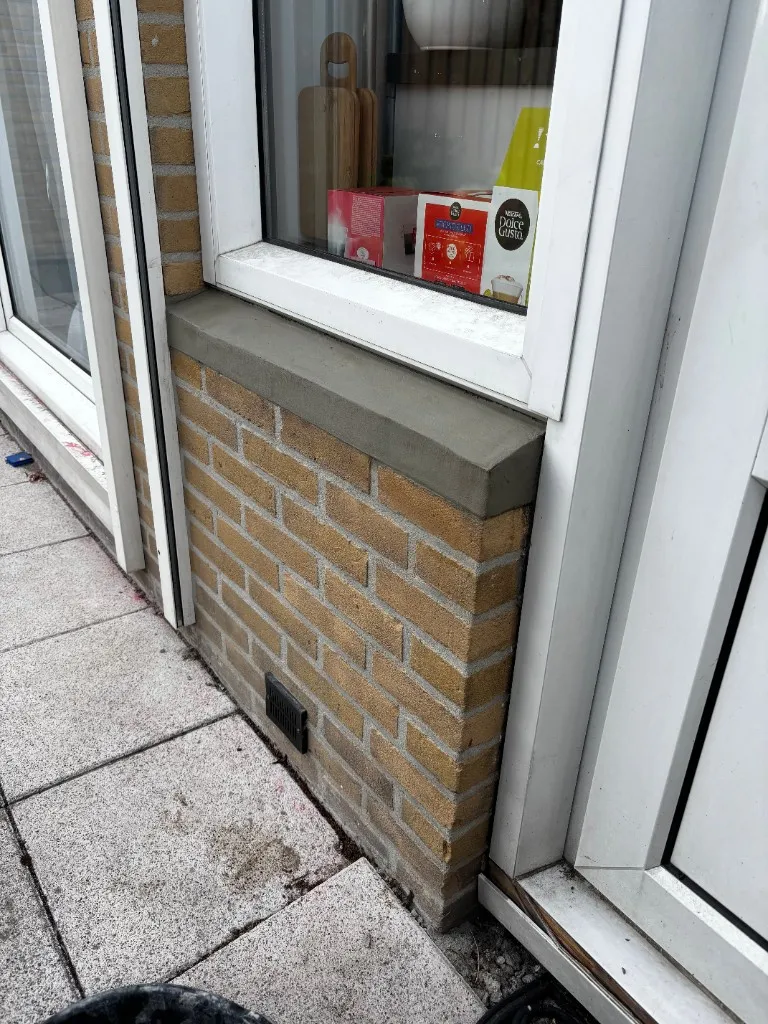 Detail na herstel: opnieuw vervoegd steenpaneel met waterlijst naar kozijn en gesmeerd dorpelvlak