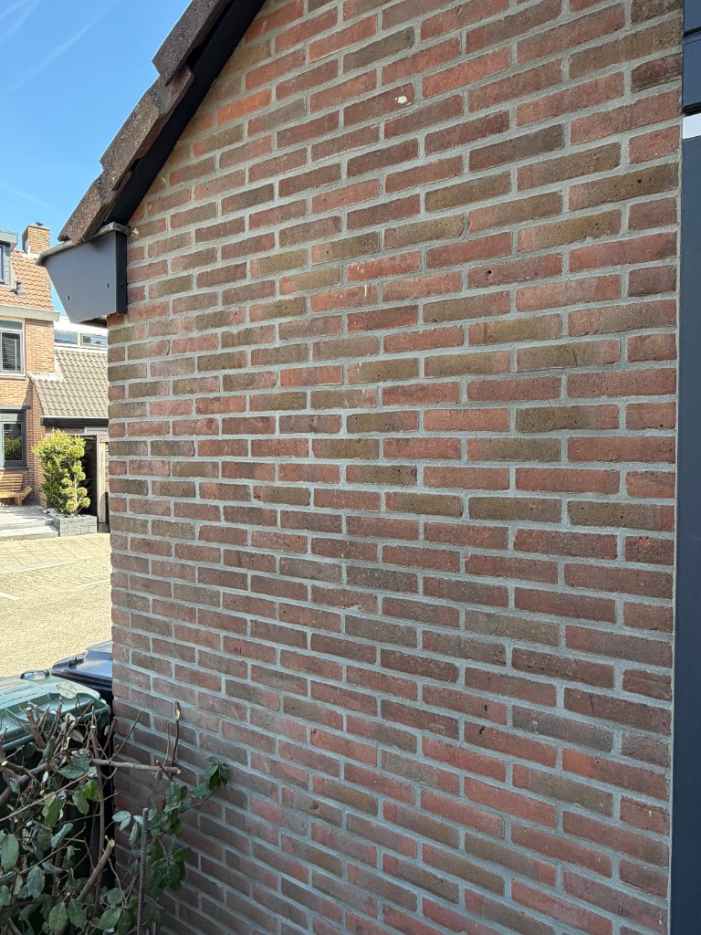 Breder zicht op snijvoeg met lichtgrijs profiel op rode baksteen