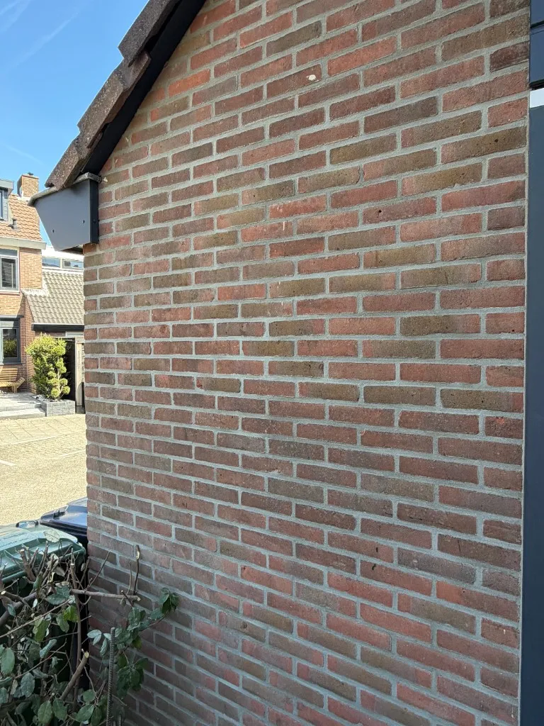 Breder zicht op snijvoeg met lichtgrijs profiel op rode baksteen
