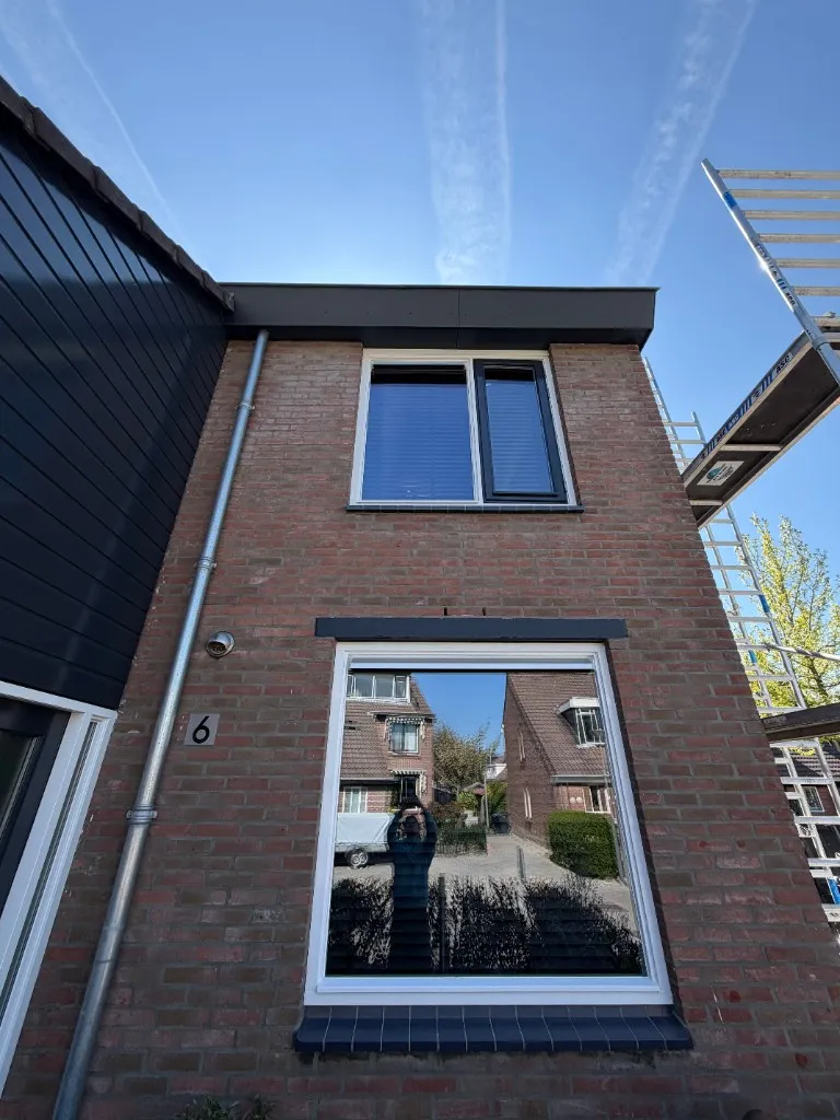 Voorgevel tijdens uitvoering: gevelrenovatie met steiger tegen rode bakstenen gevel