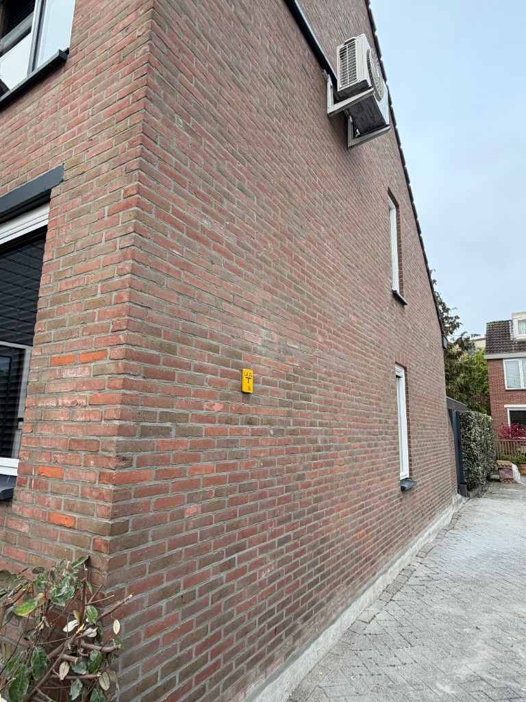 Zijgevel hoekwoning tijdens voorbereiding van het voegwerk op rode baksteen