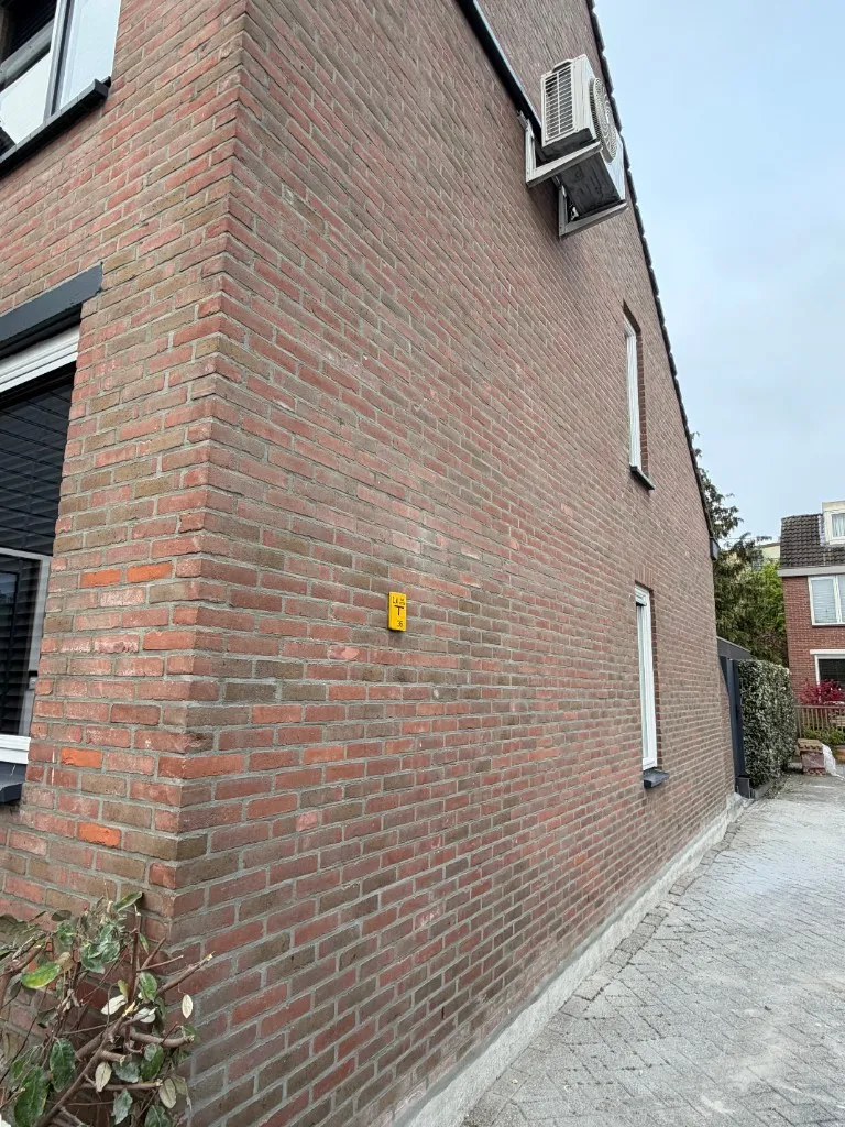 Zijgevel hoekwoning tijdens voorbereiding van het voegwerk op rode baksteen